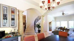 Un amplio salón con una mesa de comedor, sillas, una escalera y un ventanal grande.