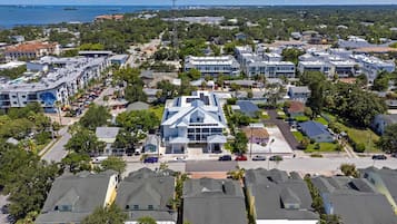 A residential area with houses, a central building with a unique roof design, and a clear view of the sea in the background.