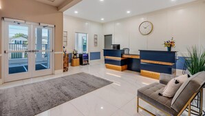 A hotel lobby with a reception desk, a clock, a sofa, and a large window. - The Grant Street Inn Dunedin Downtown Historic District, an Ascend Collection Hotel (Dunedin)