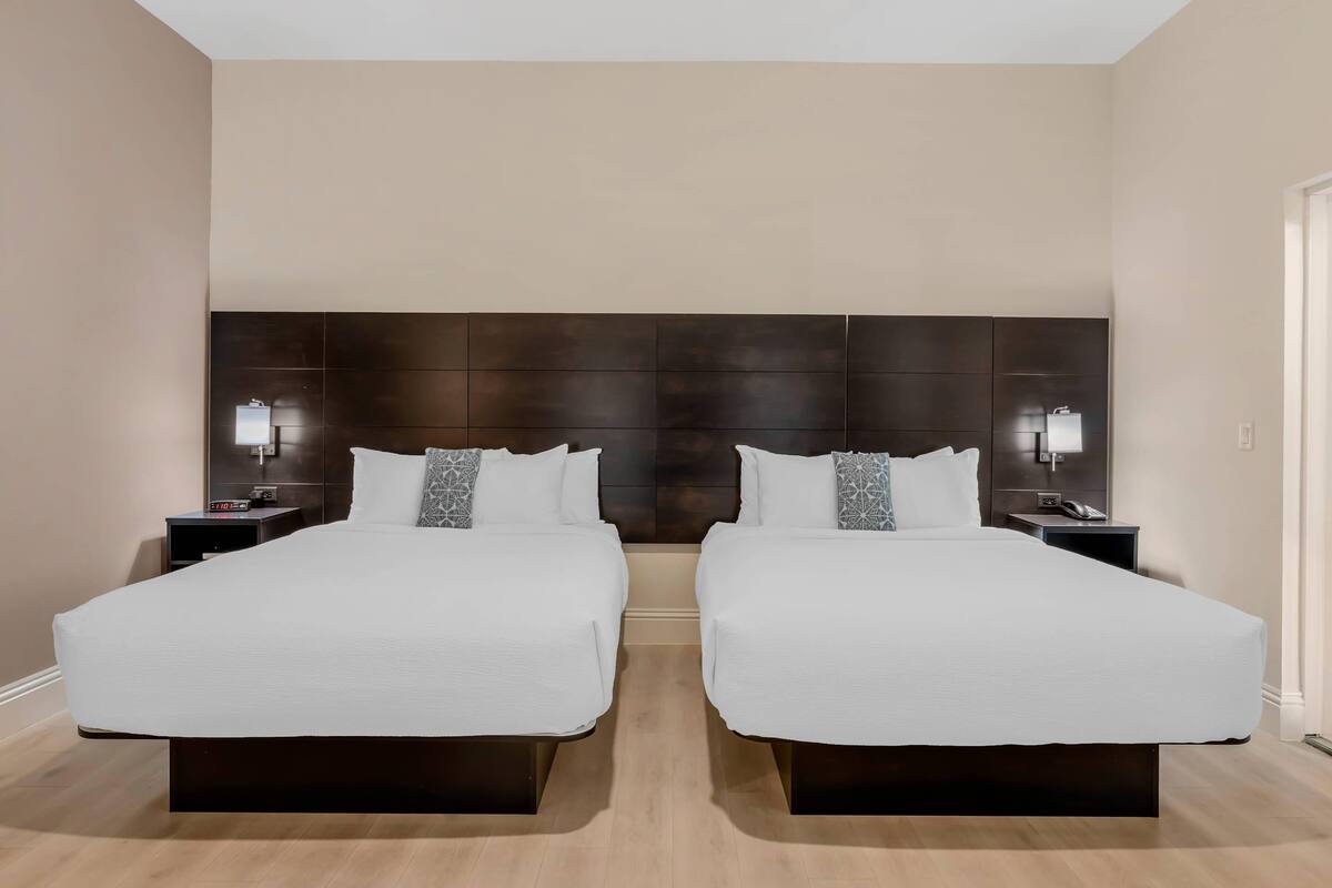 A double room with two beds, a dark headboard, bedside lamps, and a clock on the nightstand.