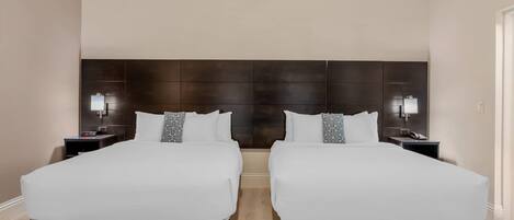 A double room with two beds, a dark headboard, bedside lamps, and a clock on the nightstand.