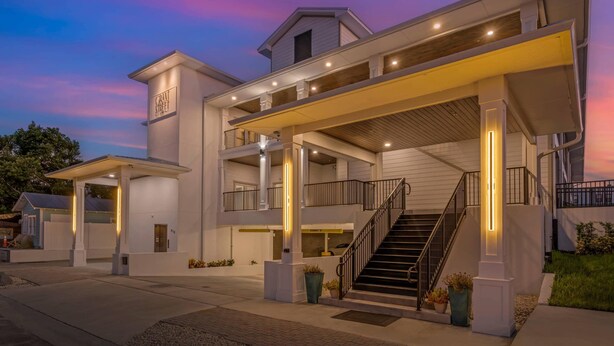 A multi-story hotel with a covered entrance, outdoor seating area, and a staircase leading to the upper levels. - The Grant Street Inn Dunedin Downtown Historic District, an Ascend Collection Hotel (Dunedin)
