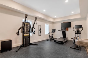 A home gym with exercise equipment, a television, and a small refrigerator.