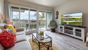 Een moderne woonkamer met een bank, een glazen salontafel, een flatscreen televisie en een balkon met uitzicht.