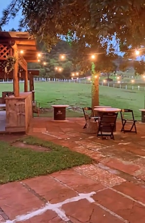 An outdoor patio area with stone flooring, wooden tables, and chairs. - Cabanas Arena SG (Gramado)