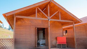 Eine Holzhütte mit überdachter Veranda, einem Bett und einer roten Bank.