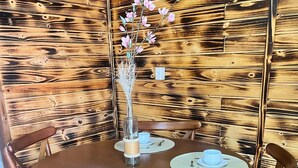 Ein Holzesstisch mit vier Stühlen, einer Vase mit Blumen und einer Tischmatte mit Tasse und Gabel.