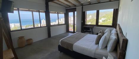Ein Schlafzimmer mit einem großen Bett, einem Deckenventilator und Meerblick.