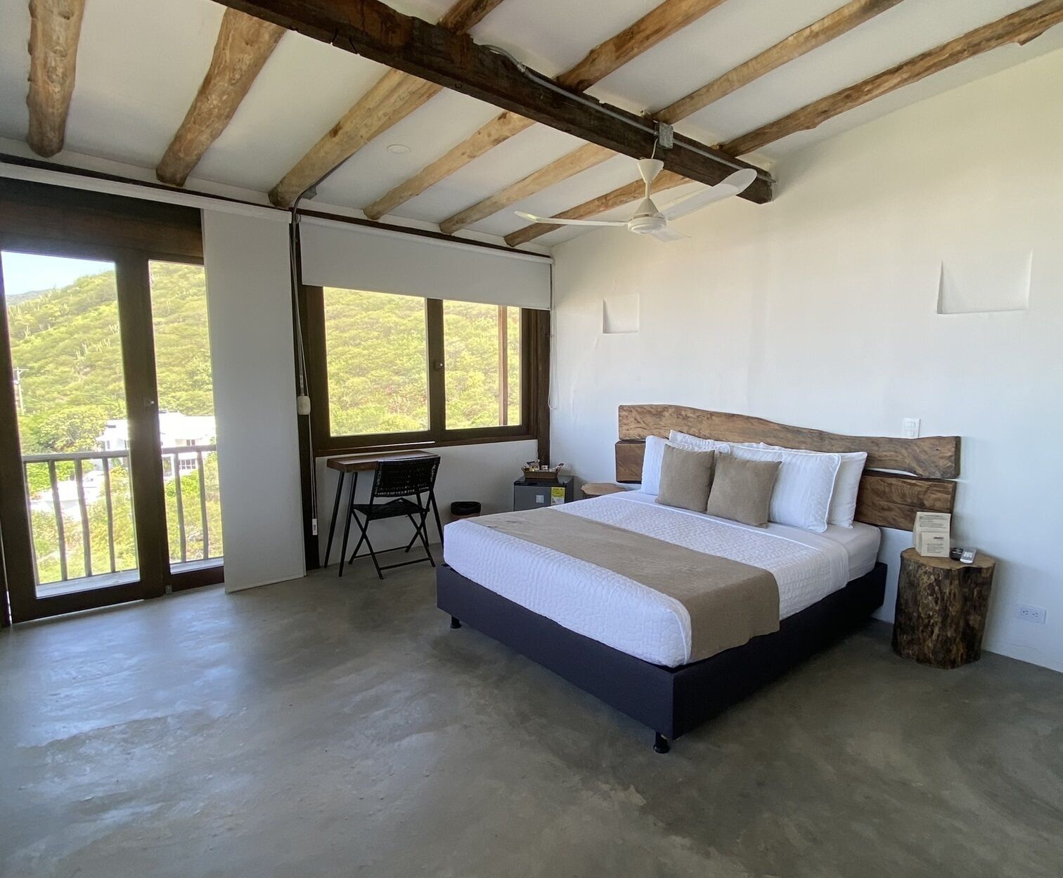 Ein Schlafzimmer mit einem großen Bett, einem Schreibtisch und Blick auf Grünfläche.