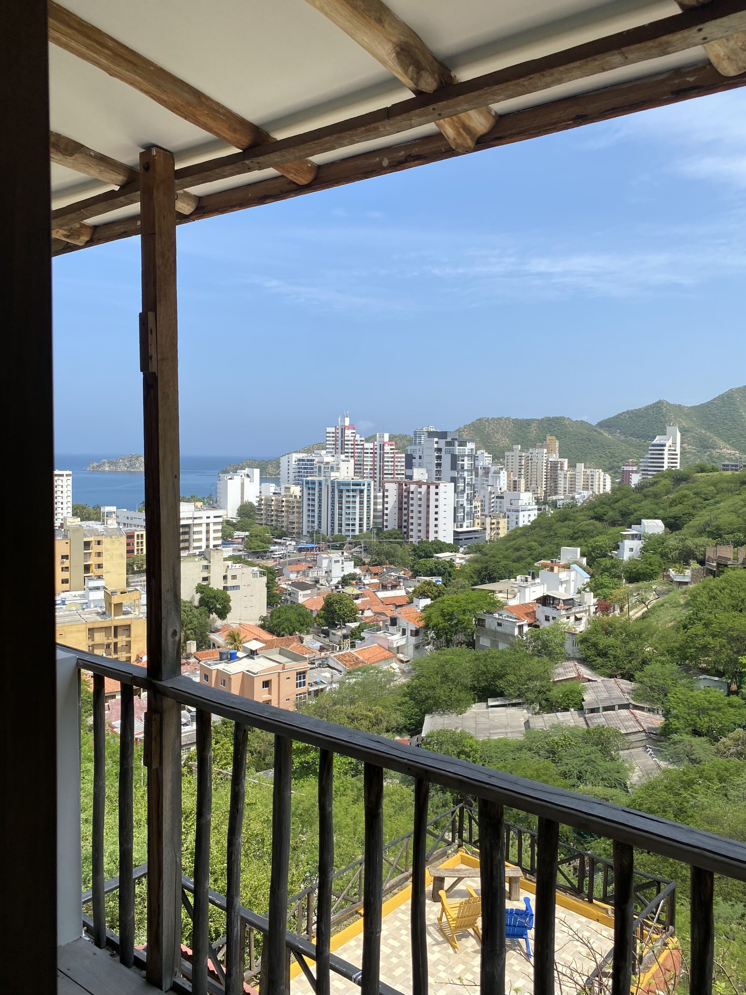A balcony with a view of a cityscape, including buildings and greenery.