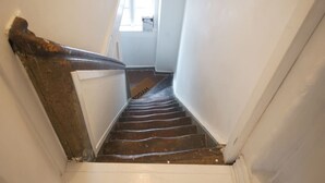 Eine schmale Treppe mit Holzdielen, die zu einer Zwischenebene führt.