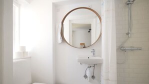 A bathroom with a toilet, a sink, a mirror, and a shower. - LBS 3 · Copenhagen Hotel Apartments (København)