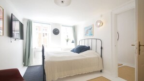 Un dormitorio con una cama, una silla, un reloj y una puerta.