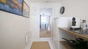 Un pasillo estrecho con un radiador, un reloj y un cuadro en la pared.