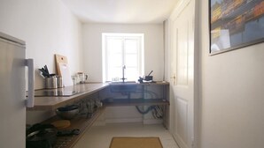 Una cocina estrecha con ventana, un lavabo y una encimera con utensilios de cocina.