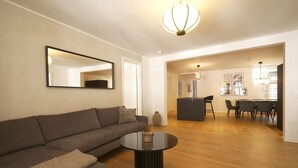 A modern living room with a sofa, a round coffee table, and a dining area with chairs and a table.