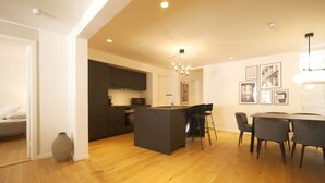 A modern kitchen with dark cabinets, a central island, and a dining area with a table and chairs.