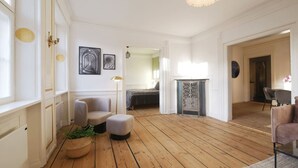 A spacious living room with wooden flooring, a fireplace, and a dining area with a table and chairs. - New Harbour / Carolina's Apartments / 2 BR (København)