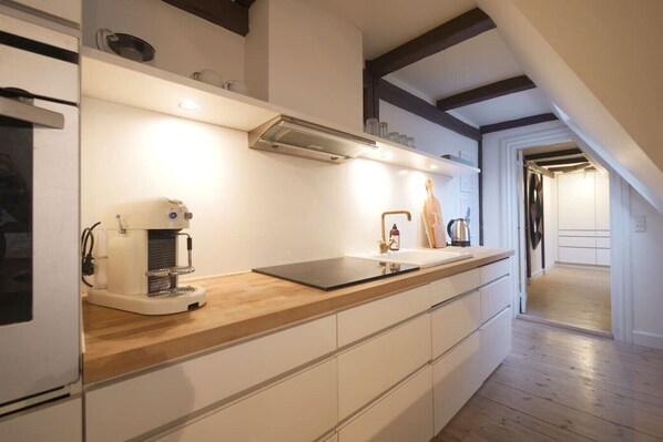 A modern kitchen with a built-in coffee machine, a sink, and wooden countertops.