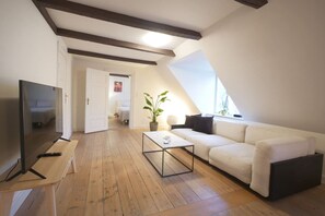 A modern living room with a TV, sofa, coffee table, and a plant.