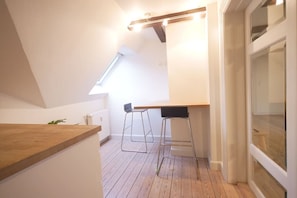 A small, bright room with a sloped ceiling, a wooden counter, two bar stools, and a skylight.