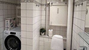 A compact bathroom with a toilet, sink, and washing machine.