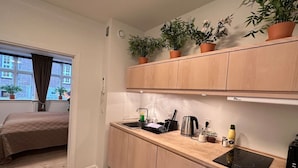 A compact kitchen with wooden cabinets, a built-in stove, and a window with curtains.