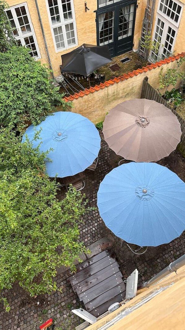 Un patio con tres sombrillas, una terraza de madera y un muro de ladrillo.