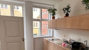 A small kitchen with wooden cabinets, a window, and a door.