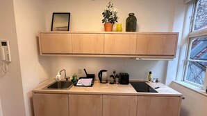 Een kleine keuken met een spoelbak, aanrecht en houten keukenkastjes.