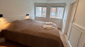 Une chambre à coucher avec un grand lit, deux fenêtres et une porte.