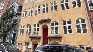Ein mehrstöckiges Gebäude mit einer roten Tür und mehreren Fenstern.