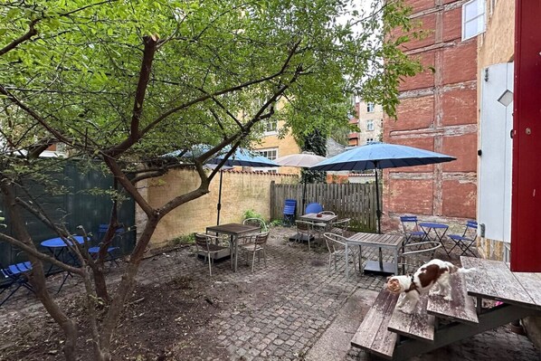 A patio area with outdoor furniture, a tree, and a red door.
