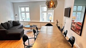 A modern dining area with a long table, black chairs, and pendant lighting. - Main shopping street RAP 7 (København)