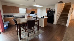 A spacious kitchen with wooden cabinets, a granite countertop, and a dining area with a rug. - Spacious 5BR • 11 Beds • Sleeps 15 • Fenced Yard w/Grill – Great July Rates! (Pflugerville)