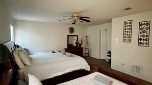 A bedroom with two beds, a ceiling fan, a dresser, and wall decorations. - Spacious 5BR • 11 Beds • Sleeps 15 • Fenced Yard w/Grill – Great July Rates! (Pflugerville)