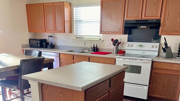 A kitchen with wooden cabinets, a built-in microwave, a stove, and a sink. - Spacious 5BR • 11 Beds • Sleeps 15 • Fenced Yard w/Grill – Great July Rates! (Pflugerville)