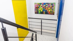 A staircase with a yellow door on the left, a blue door on the right, and a colorful abstract painting on the wall. - Casa Colors (Cartagena)