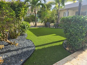 Un jardín bien cuidado con césped, zona de estar y diversas plantas.