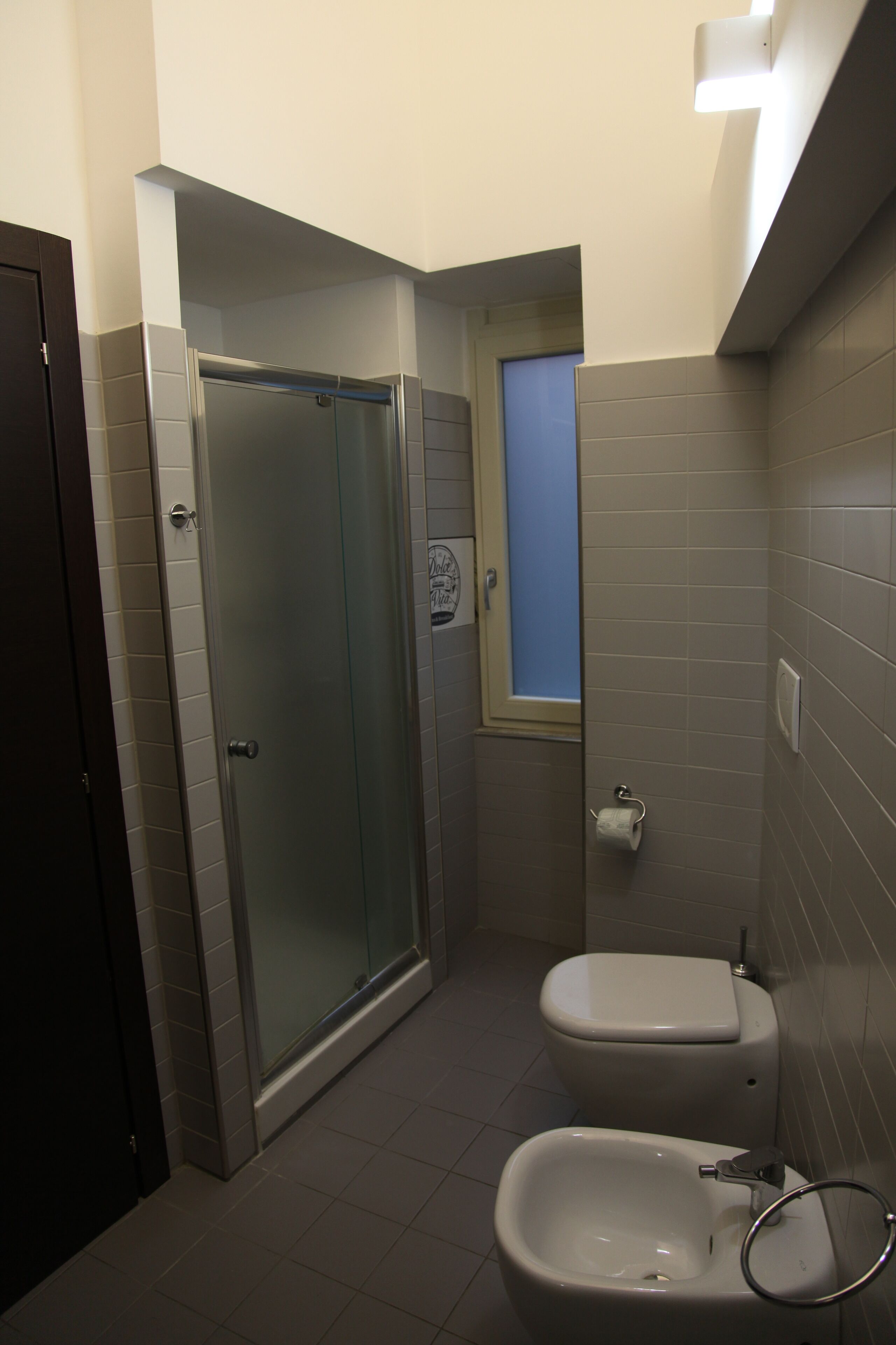 A compact bathroom with a glass-enclosed shower, a toilet, and a sink.