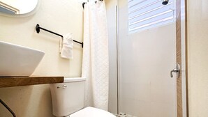 A bathroom with a toilet, a sink, and a shower area. - Two floor combo unit (San Juan)