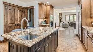 A kitchen with wooden cabinets, granite countertops, and a central island with a sink. - Gorgeous Mountain Residence, Spectacular Views, Fire Pit (Vail)