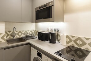 A compact kitchen with a built-in microwave, a toaster, and a kettle.