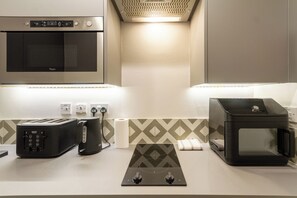 A kitchenette with a microwave, toaster, kettle, and a gas stove.