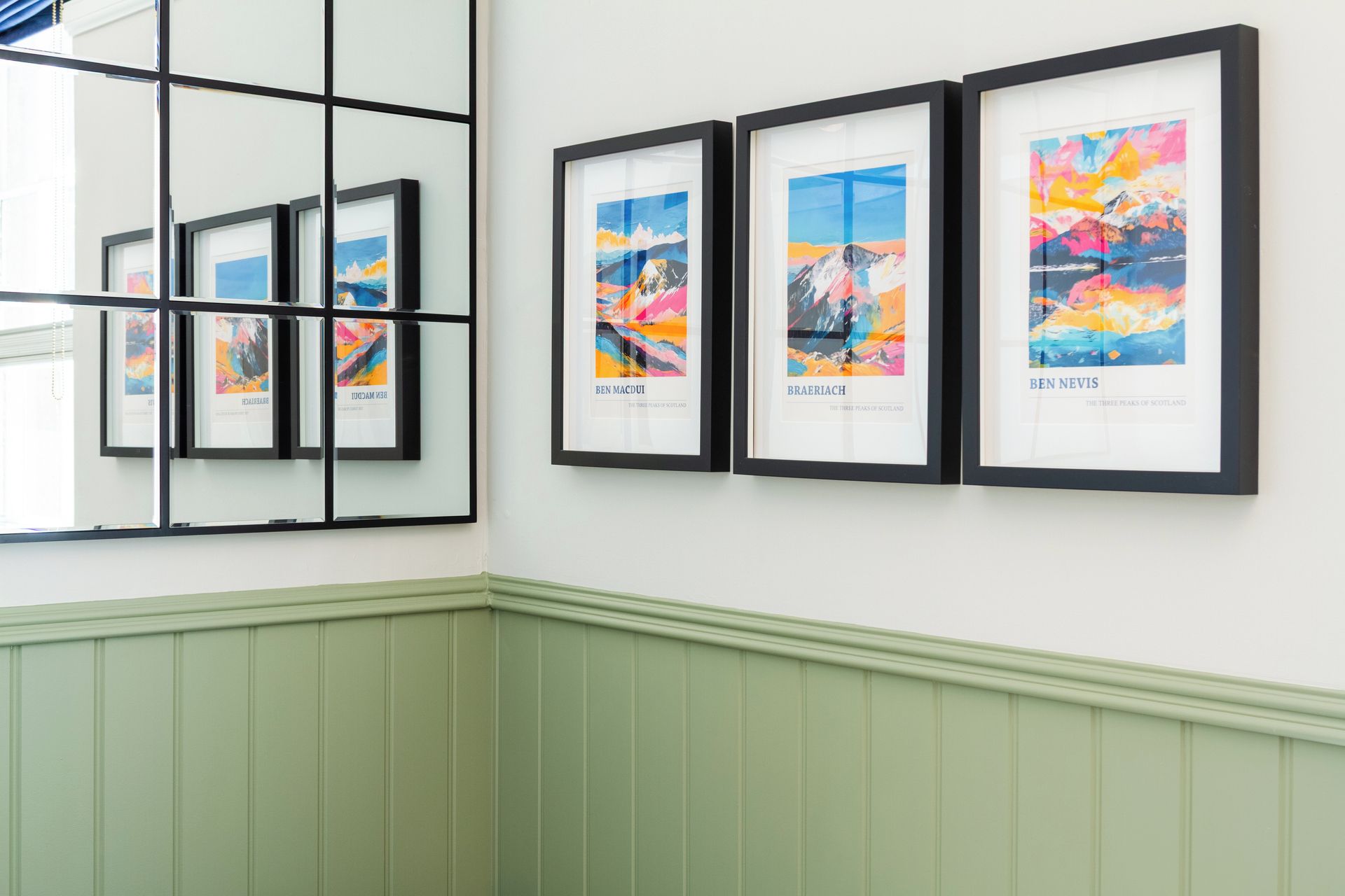 A wall with framed artworks and a green wainscoting.