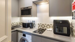 Cocina compacta con microondas, tostadora, hervidor y horno pequeño.