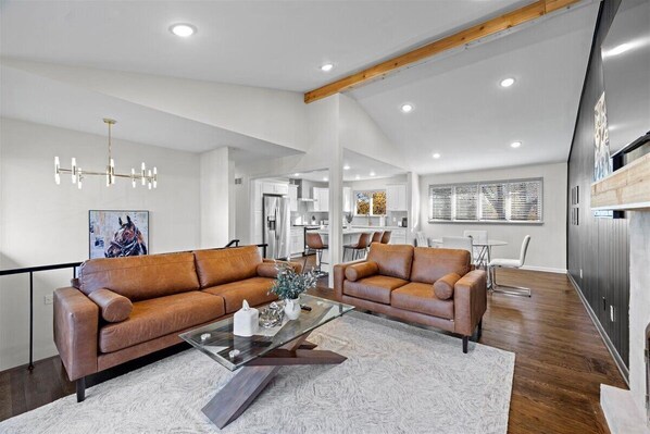 A modern living room with leather sofas, a glass coffee table, and a large window.