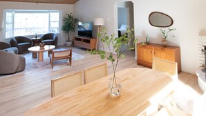 Amplia sala de estar con techo de madera, comedor con una gran mesa y un televisor al fondo.