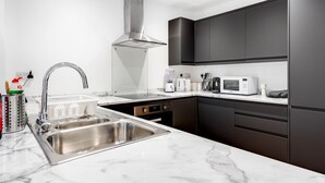 Una cocina moderna con un lavamanos de acero inoxidable, armarios negros, una estufa integrada y un microondas.