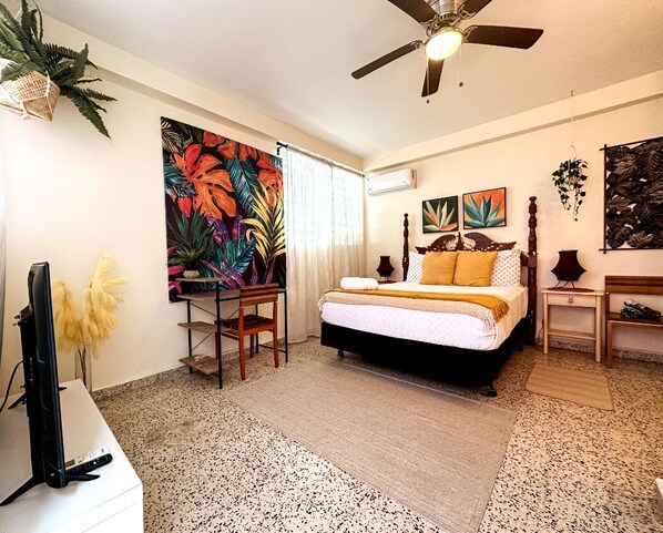Ein Schlafzimmer mit einem Bett, einem Deckenventilator, einem Fernseher und Kunstwerken an den Wänden.